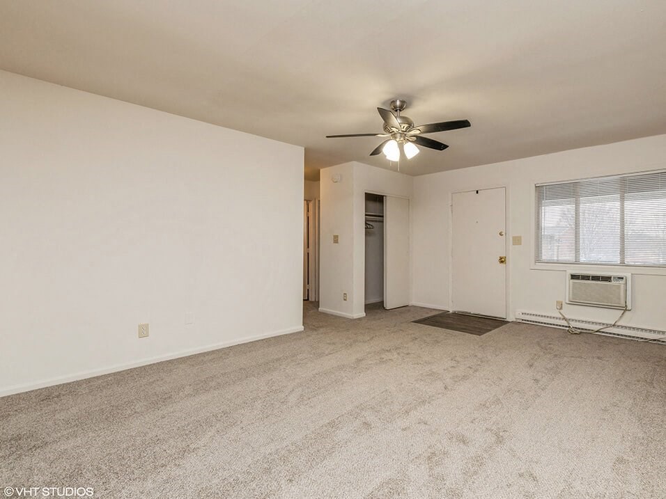 an empty living room with a ceiling fan and a window