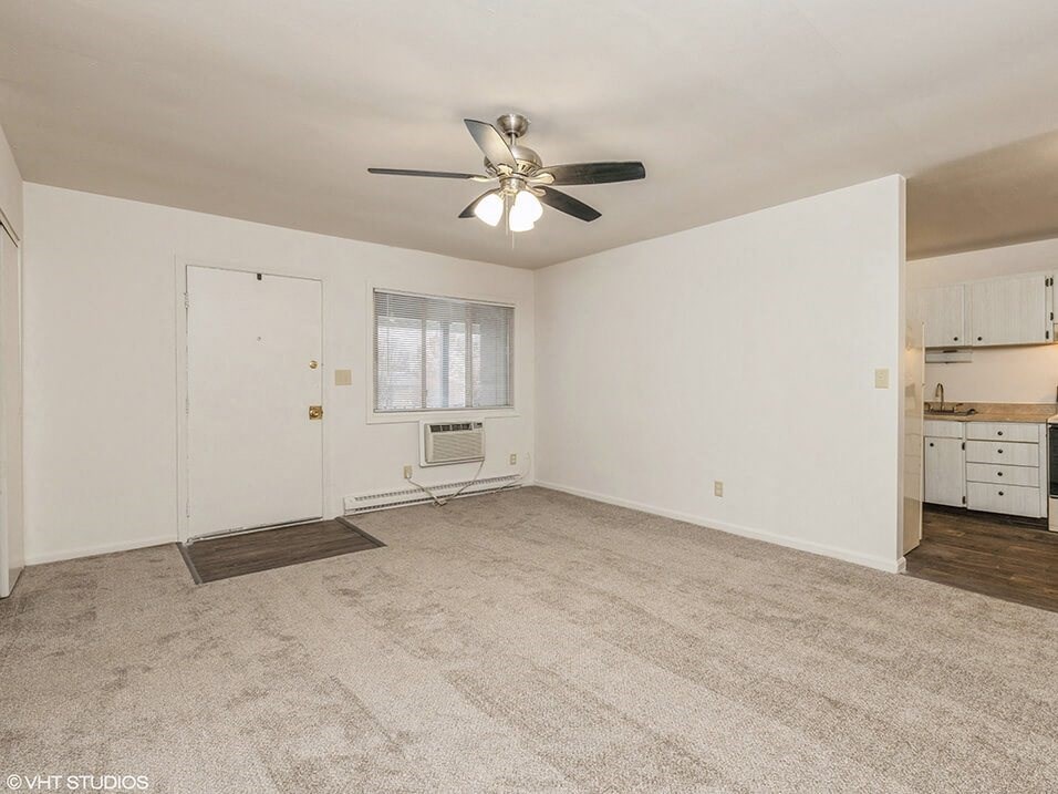 an empty living room with a ceiling fan
