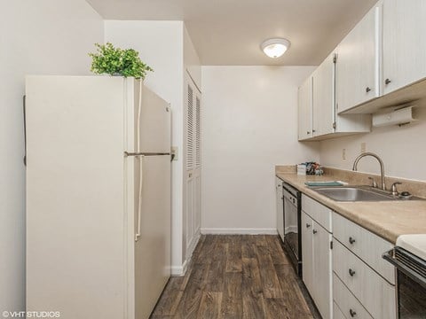 a small kitchen with white cabinets and a refrigerator