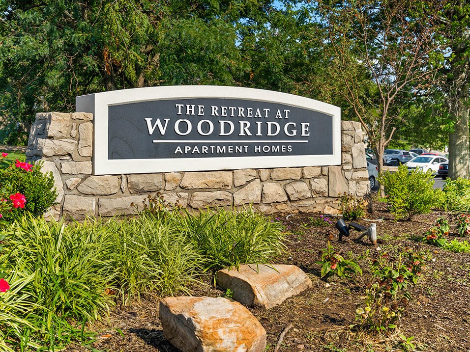Welcome sign for The Retreat at Woodridge Apartments
