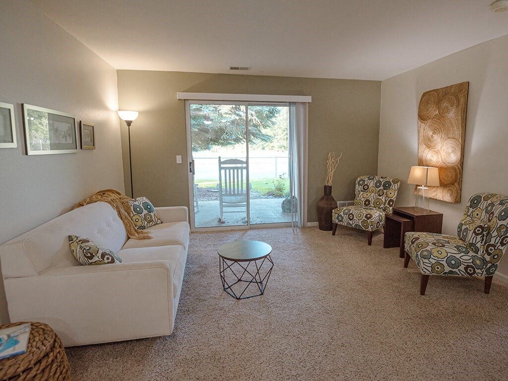 a living room with a couch and chairs and a sliding glass door