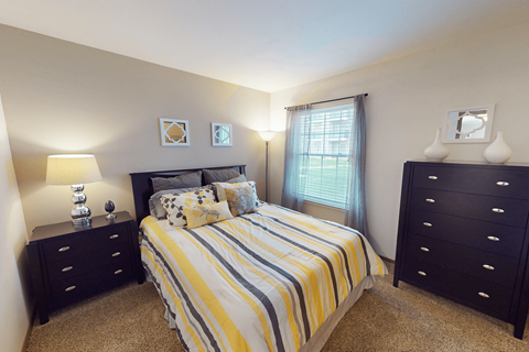 A bedroom with a bed, two nightstands, and a window.