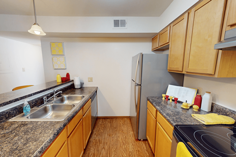 A kitchen with a refrigerator, sink, and stove.