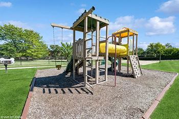 a playground with a yellow swing set in a park