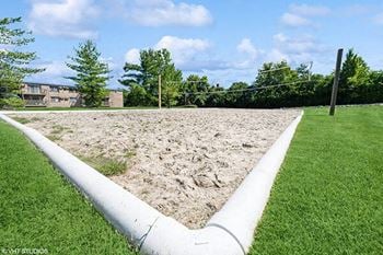 a sand volleyball court in the middle of a grass field