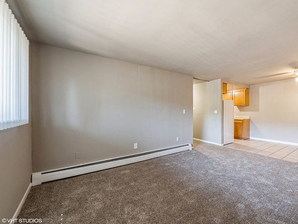 an empty living room with a large window and carpet