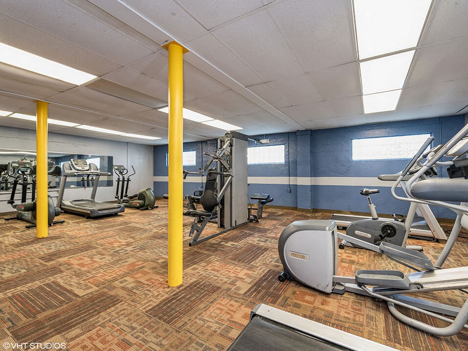 a gym with various machines and weights in an apartment complex