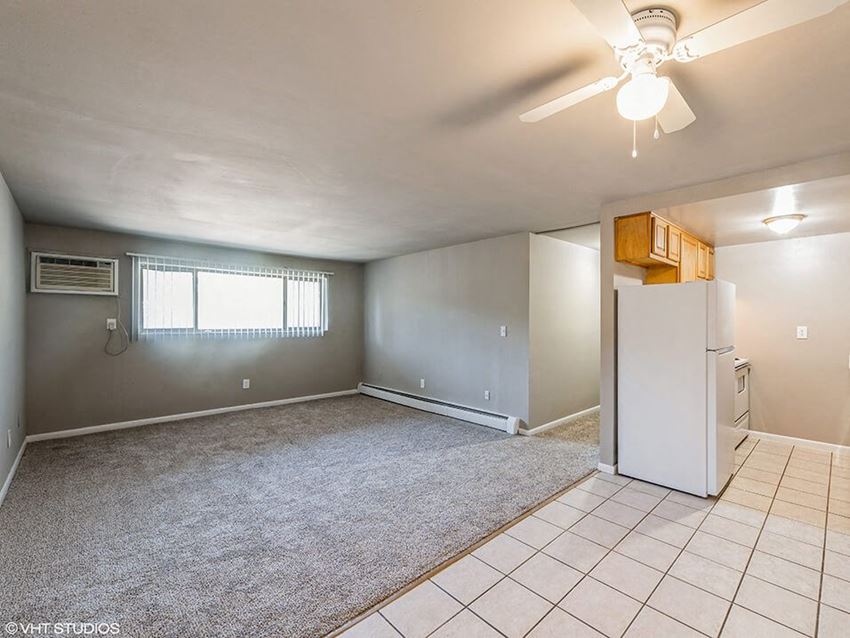 an empty living room with a white refrigerator