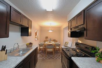 A kitchen with a dining table and chairs in the middle.