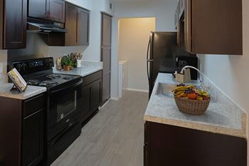 A kitchen with black appliances and brown cabinets.