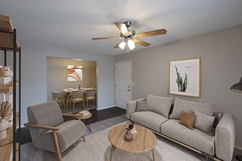 A living room with a grey couch, a wooden chair, and a ceiling fan.