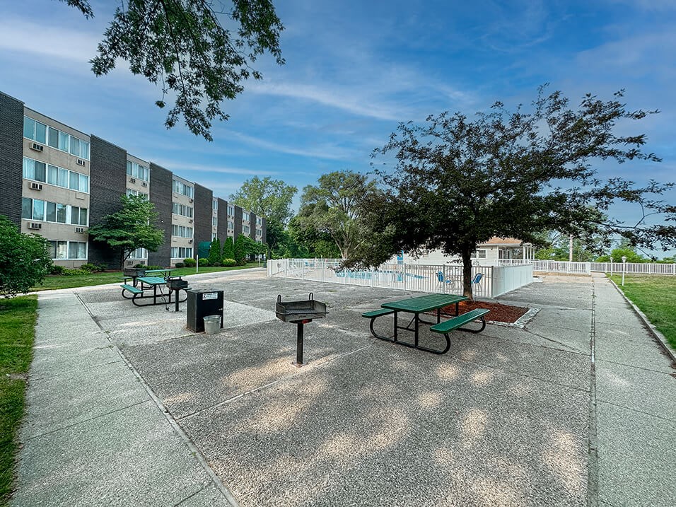 a park with benches and a fountain in front of an apartment building