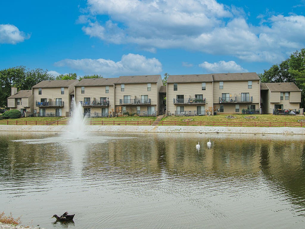 a duck swimming in a pond in front of an apartment building