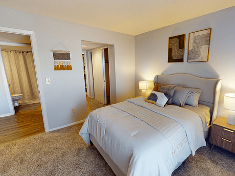 A bedroom with a large bed and two lamps.