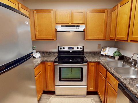 A kitchen with wooden cabinets and a stainless steel refrigerator.