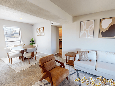 A living room with a white couch, a brown chair, and a small table with a plant on it.
