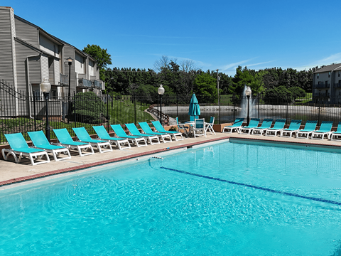 A swimming pool with blue water and lounge chairs.