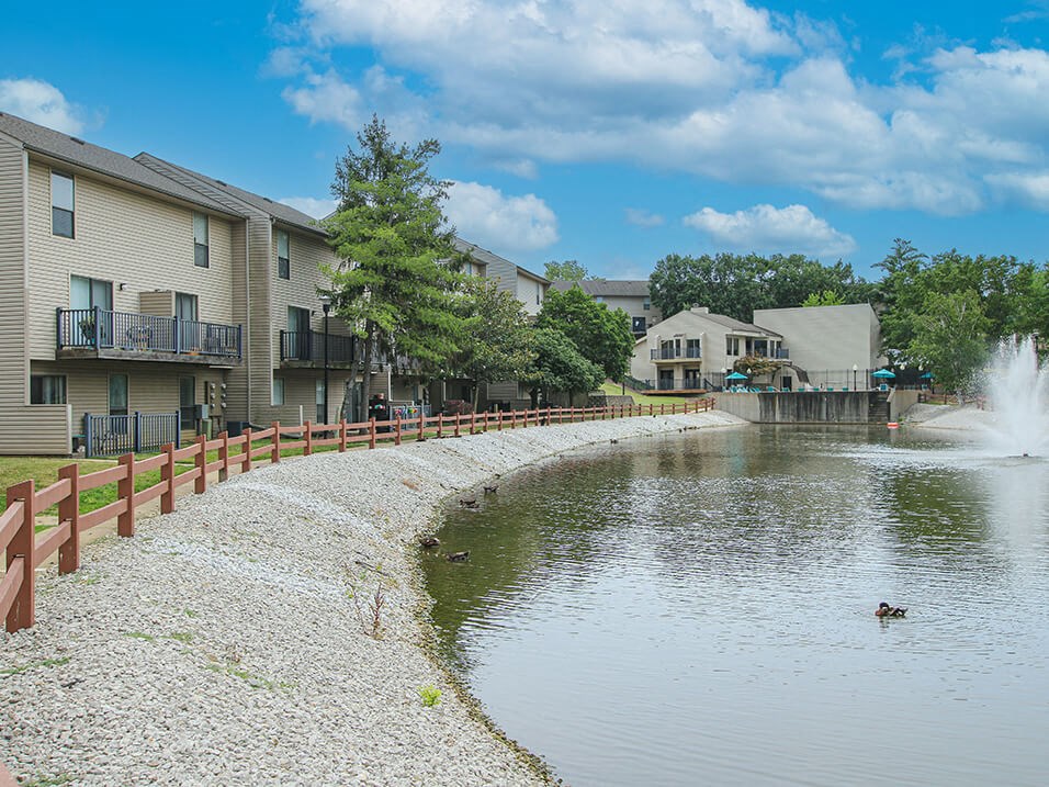 a pond with a fountain in front of a building