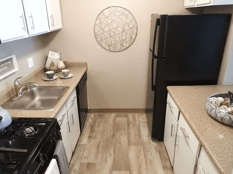 a kitchen with white cabinets and a black refrigerator