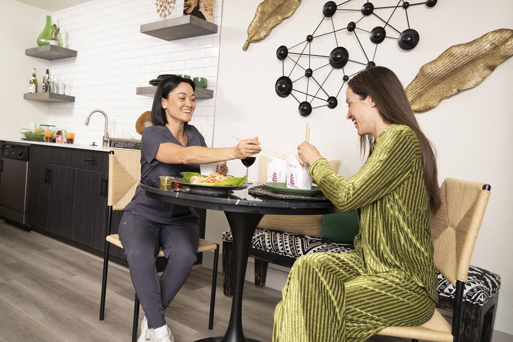 Two women are sitting at a table in a modern kitchen. at Namaste Apartments, Las Vegas