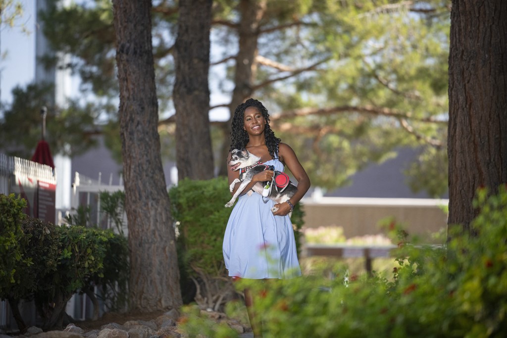 A woman in a blue dress is walking through a garden. at Solstice Apartment Homes, Las Vegas