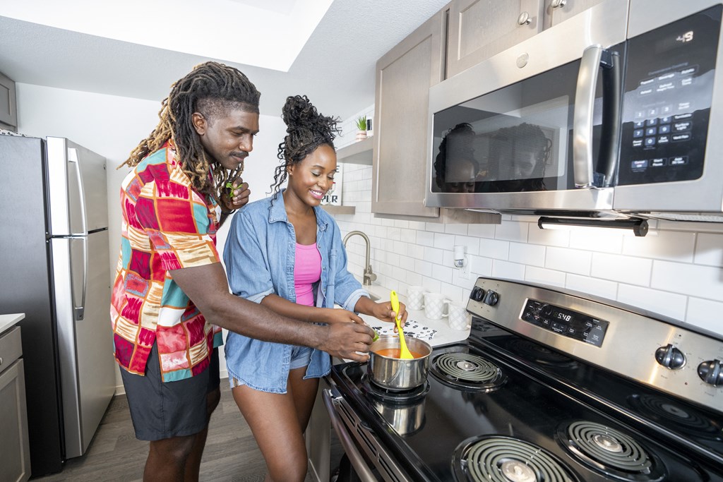 Two people cooking in a modern kitchen. at Solstice Apartment Homes, Las Vegas, NV