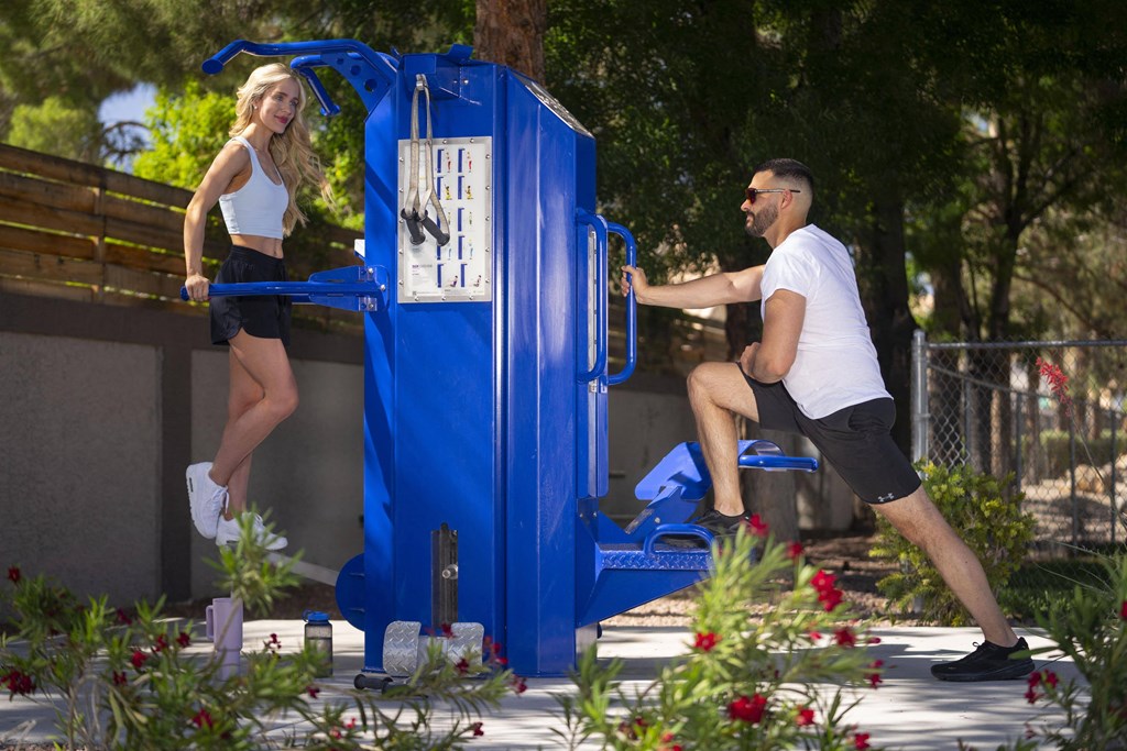 A woman in a white top and black shorts is jumping into a blue water fountain. at The 95 Apartments, Nevada, 89129