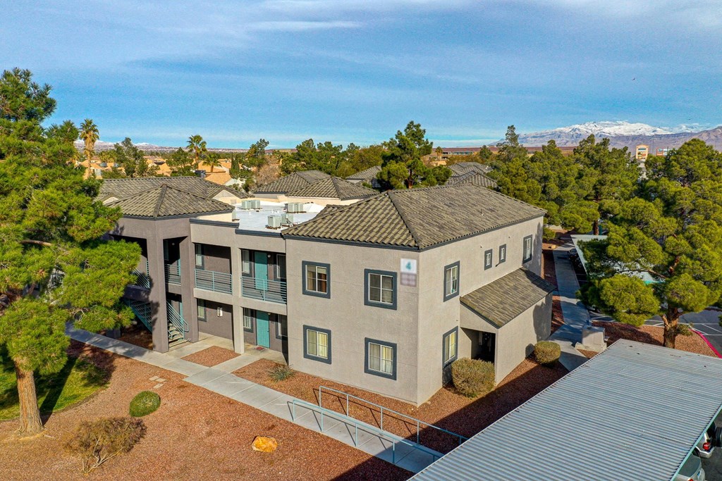 an aerial view of an apartment building with trees and a mountain in the background