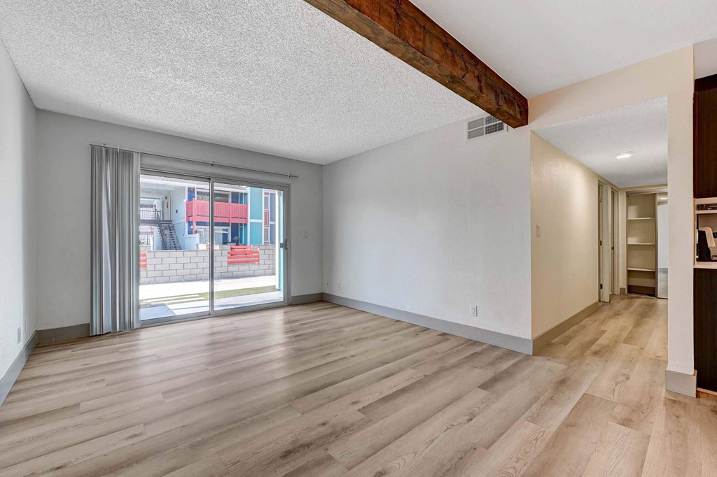 A room with wooden flooring and a sliding glass door. at Namaste Apartments, Las Vegas, NV, 89102