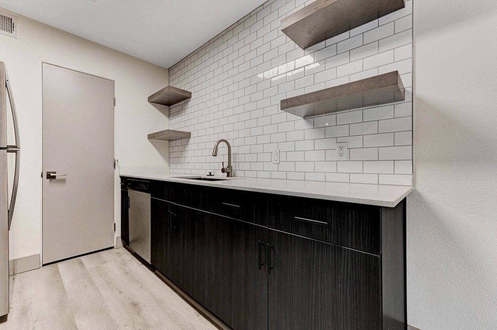 A kitchen with black cabinets and white subway tiles. at Namaste Apartments, Las Vegas, 89102