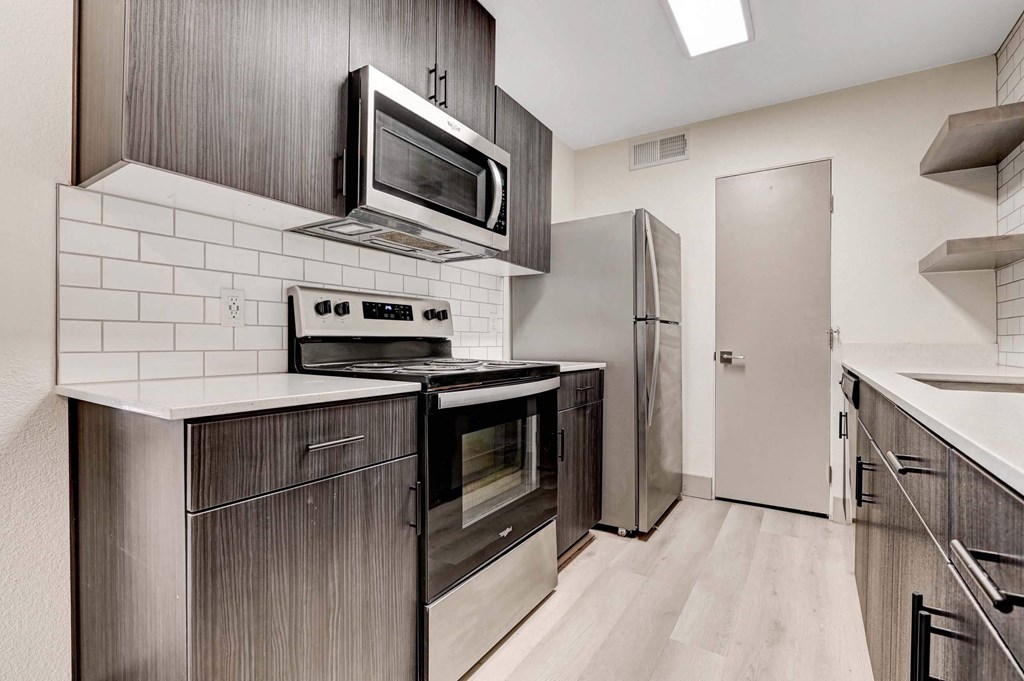 A modern kitchen with a stove top oven and microwave above it. at Namaste Apartments, Nevada, 89102