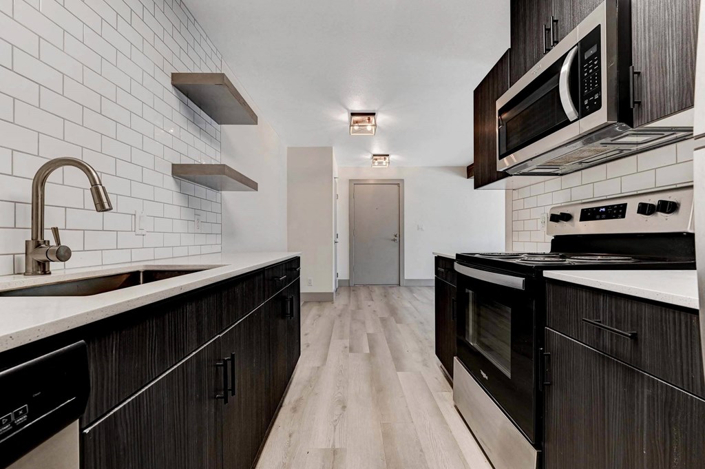 A kitchen with black cabinets and a white tiled backsplash. at Namaste Apartments, Las Vegas, NV, 89102