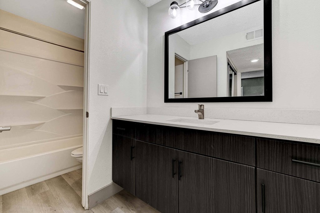 A bathroom with a white sink and a mirror. at Namaste Apartments, Las Vegas, 89102