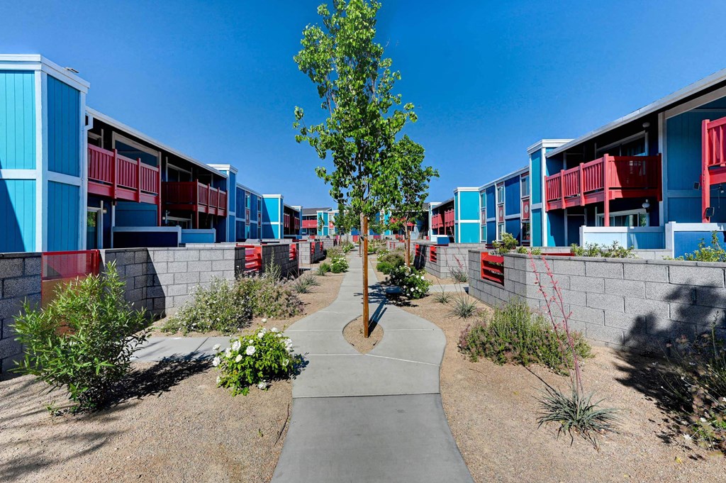A tree in a courtyard surrounded by buildings. at Namaste Apartments, Las Vegas, NV