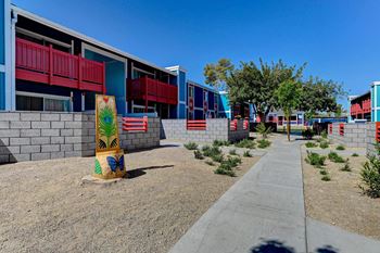 A colorful building with a red balcony and a yellow sign with a palm tree on it. at Namaste Apartments, Las Vegas, Nevada