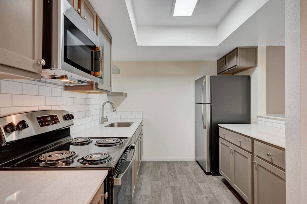 A kitchen with a black refrigerator and stove top oven. at Solstice Apartment Homes, Las Vegas, NV