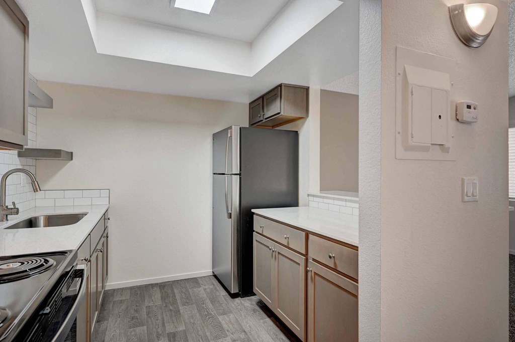 A kitchen with a stainless steel refrigerator and wooden cabinets. at Solstice Apartment Homes, Las Vegas