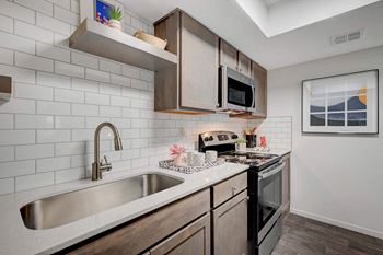 A kitchen with a white sink and black oven. at Solstice Apartment Homes, Las Vegas, NV, 89108