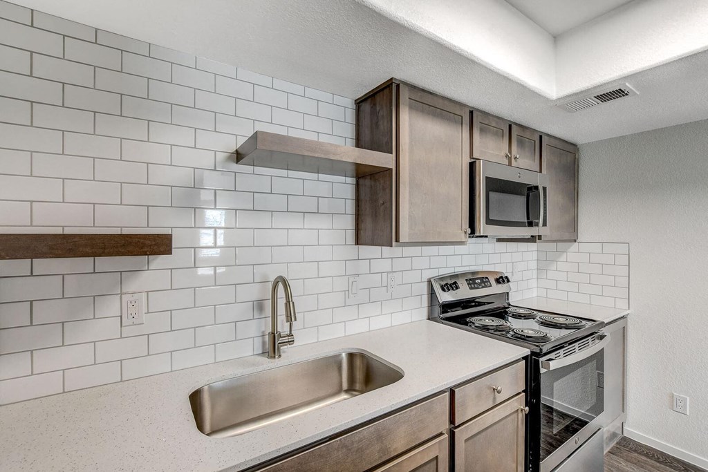 A kitchen with a stove, sink, and microwave. at The 95 Apartments, Las Vegas, NV