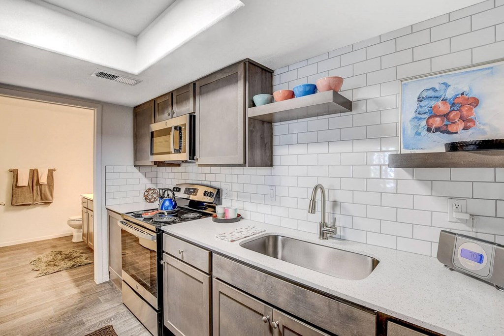 A modern kitchen with stainless steel appliances and a white tiled backsplash. at The 95 Apartments, Las Vegas, Nevada