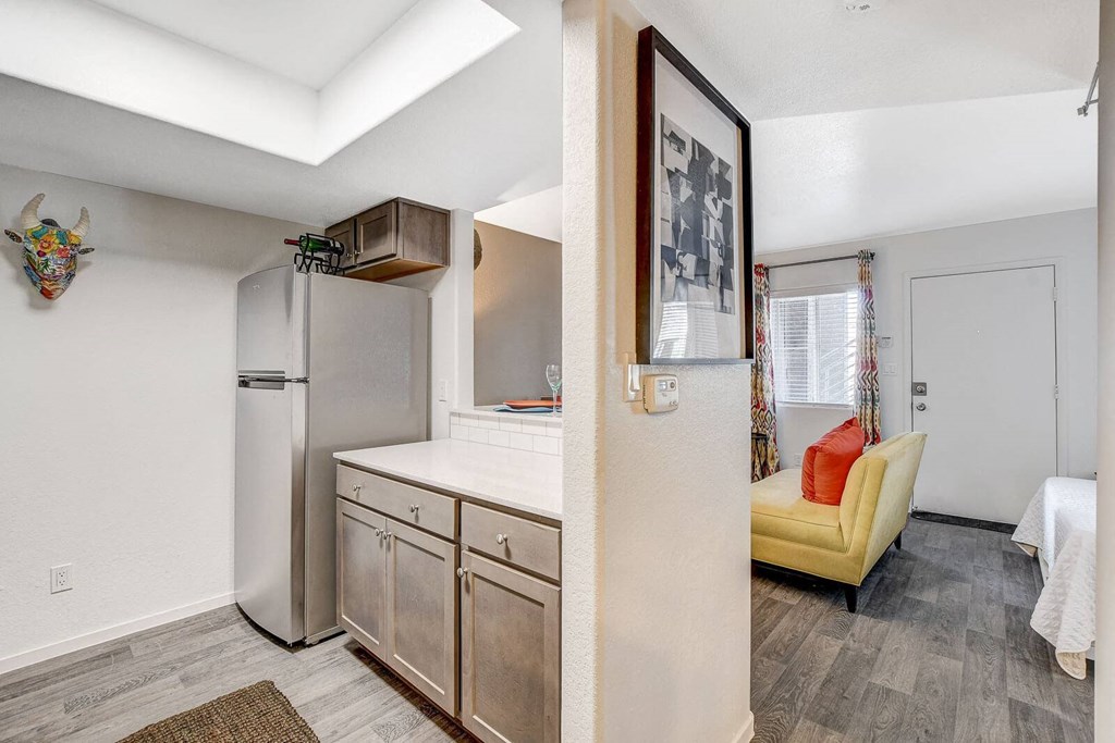 A kitchen with a refrigerator, cabinets, and a yellow chair. at The 95 Apartments, Las Vegas, NV
