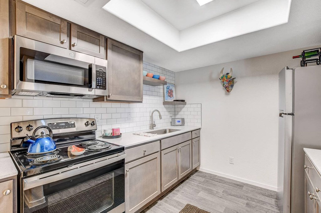 A kitchen with a stove, microwave, and refrigerator. at The 95 Apartments, Las Vegas