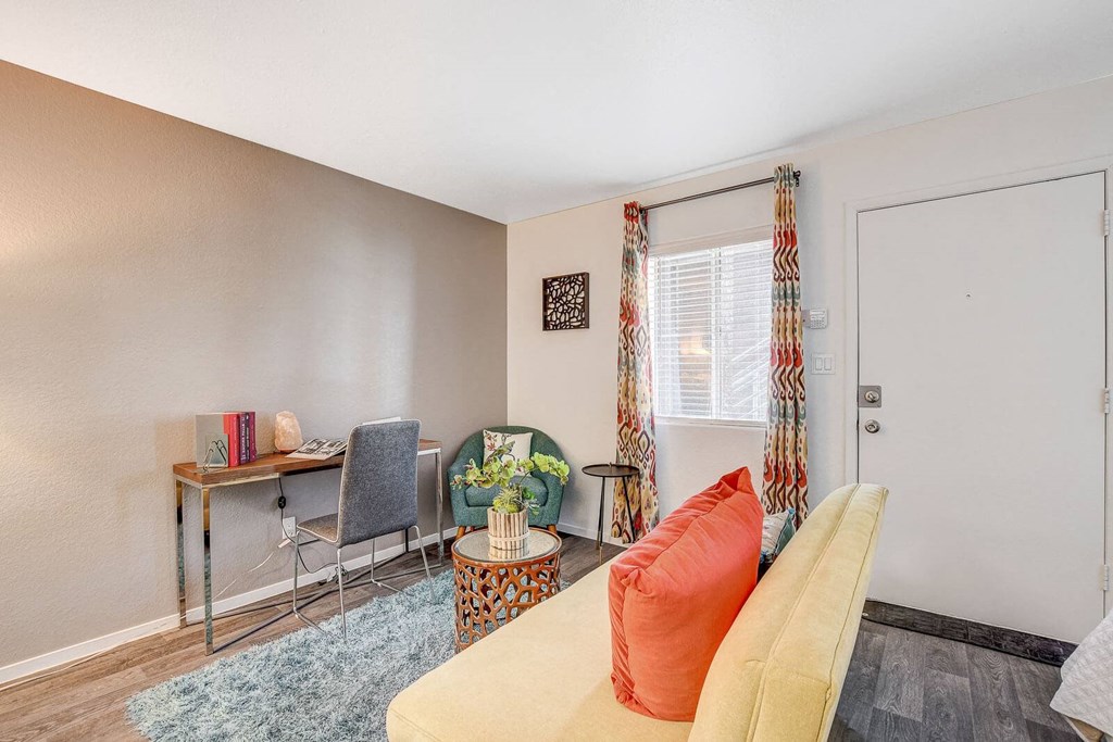 A room with a yellow couch and a desk with a chair. at The 95 Apartments, Nevada