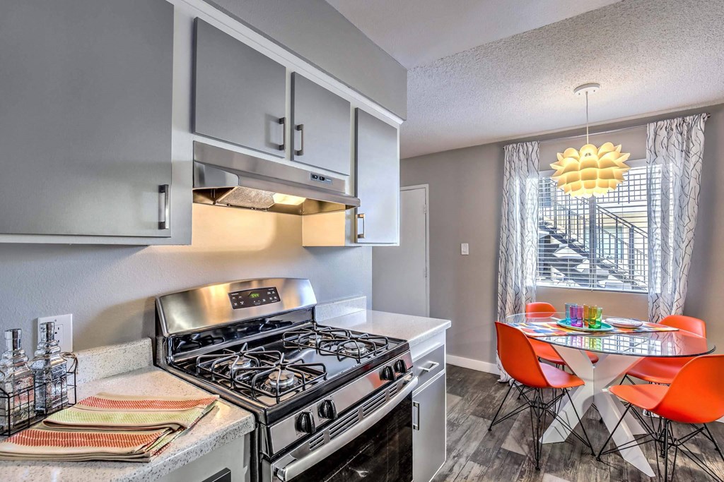 A modern kitchen with a stove top oven and a dining table with chairs. at The Neon Apartments, Las Vegas, Nevada