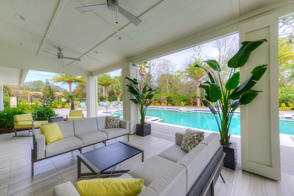 a living room with couches and a coffee table overlooking a swimming pool