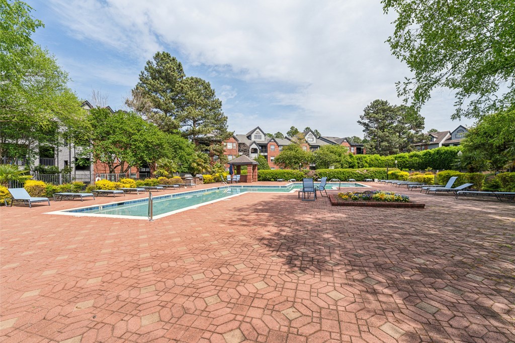 a brick patio with a swimming pool and a house in the background