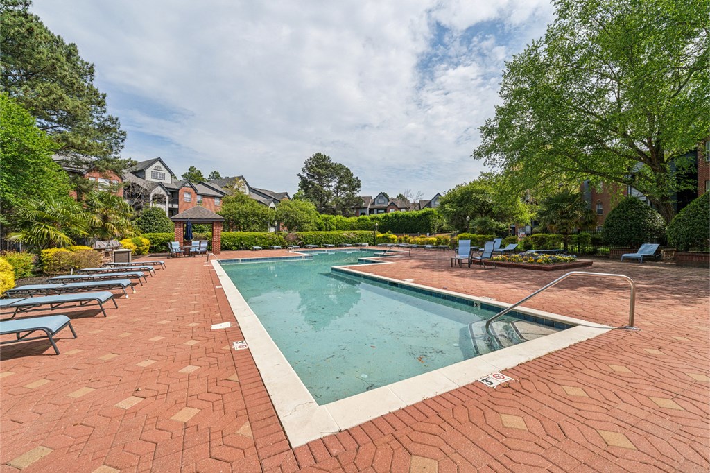 a swimming pool with lounge chairs and a house in the background