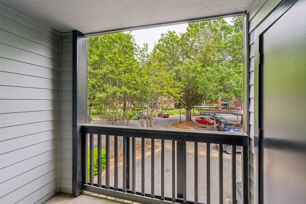 the balcony has a view of the parking lot and the trees