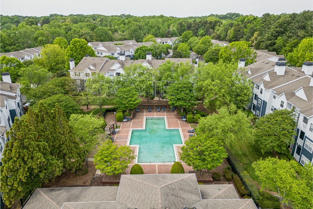 an aerial view of a swimming pool in the middle of trees and houses