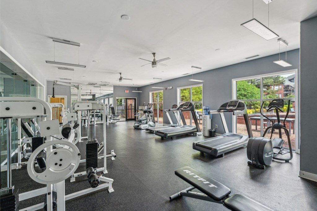a gym with weights and cardio equipment and windows